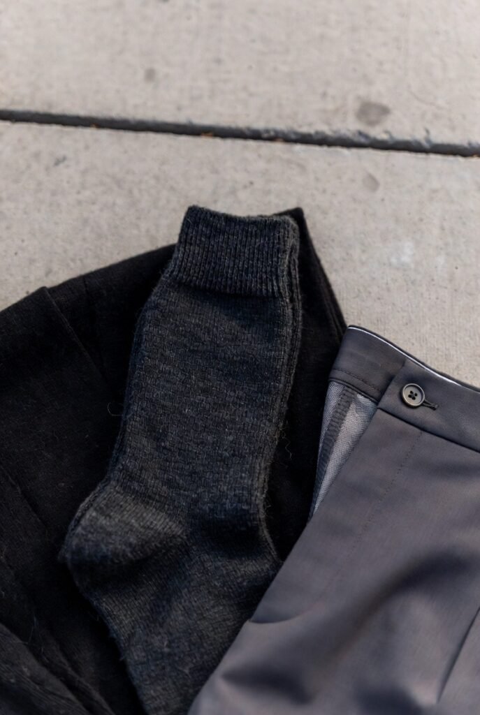 Dark wool socks folded with charcoal trousers on concrete — socks coordinate with trousers
