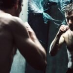 Rugged man in gritty concrete setting intensely training his mindset through shadow boxing or focused reflection. Dark moody high-contrast photography embodying masculine mental toughness, discipline, and grit. No fluff — pure signal.